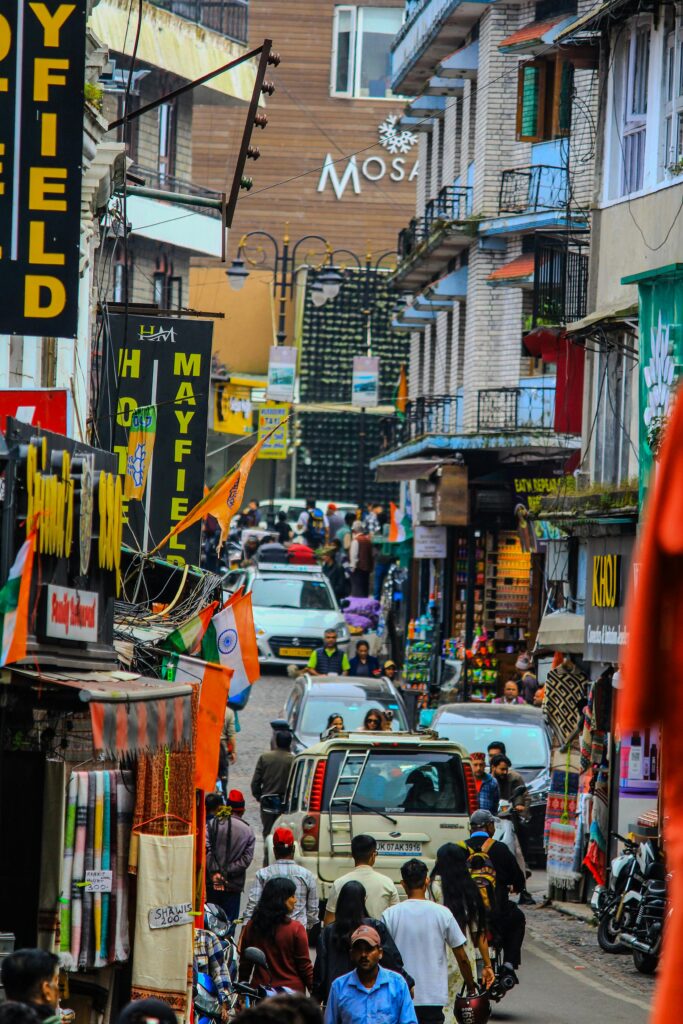 Colorful street view of the lively McLeod Ganj bazaar filled with vibrant shops, Tibetan culture, cafes and tourists exploring the famous market area near Dharamshala with Visit Taxi Service.