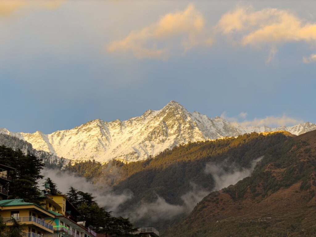 Snow-laden peak of the majestic Dhauladhar Mountains glowing under golden sunlight near Dharamshala, showcasing the scenic beauty of Himachal Pradesh for luxury taxi tours and hill station travel from Amritsar, Chandigarh, Ludhiana, New Delhi and Jalandhar by Visit Taxi Service.