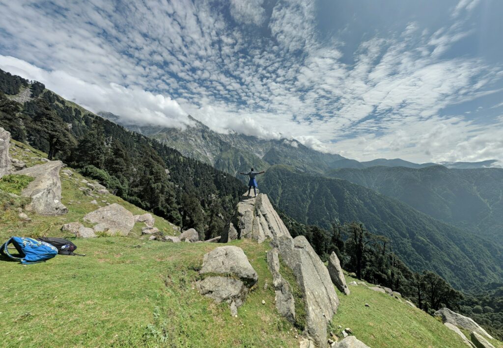 Lush green grass-covered mountains looking down at rolling hills with dense green forests, perfect for a scenic road trip with Visit Taxi.