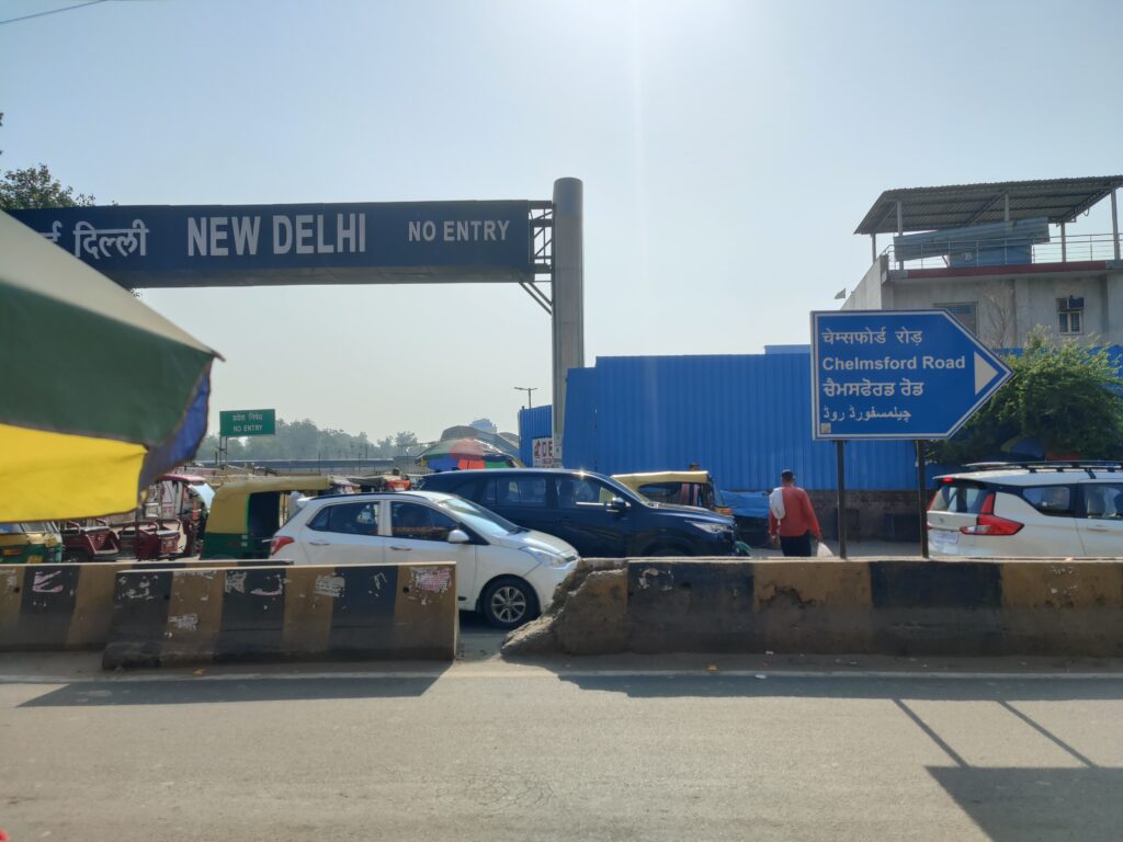 New Delhi Railway Station main entrance with travelers arriving to explore Delhi and nearby tourist attractions using Visittaxi.com transportation services.