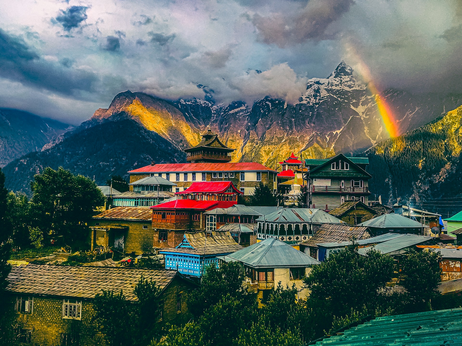 Split view of Himachal Pradesh: The lush green apple orchards of Kalpa looking towards the snow-capped Kinner Kailash peak on the left, and the stark, high-altitude desert landscape of Kaza town with Key Monastery on the right.